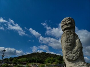 A pensive looking statue stands under the clear sky