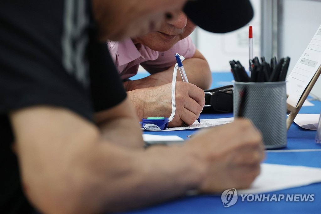 In this file photo, job seekers fill out application forms at a job fair in Seoul on June 16, 2026. (Yonhap)