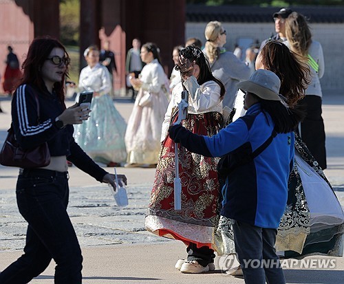 Foreign tourists, some dressed in the traditional Korean attire of "hanbok," take photos while visiting Gyeongbok Palace in central Seoul, in this undated file photo. (Yonhap)